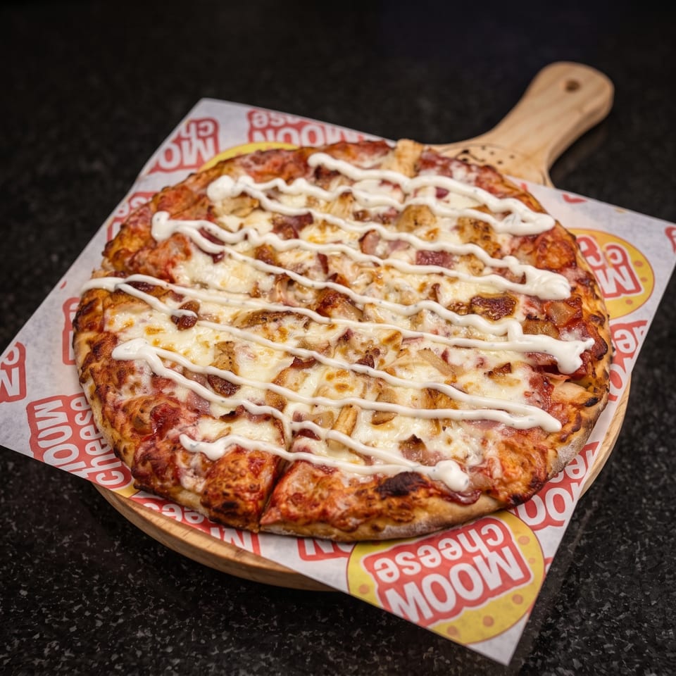 Loaded pizza topped with melted cheese, pepperoni, diced meat, and white sauce on a wooden serving board.